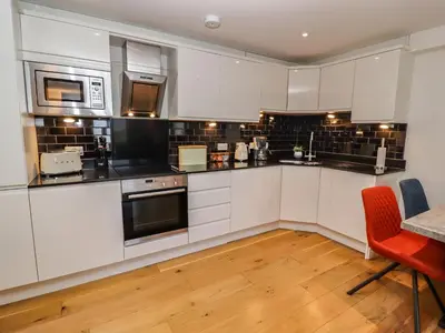 a kitchen with white cabinets and a table and chairs at The View in St Ives