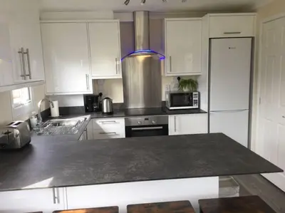 a kitchen with white cabinets and a counter top at Marios Lodge in Padstow