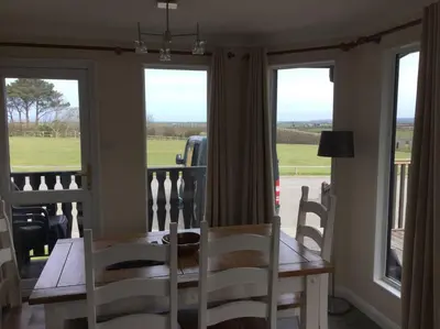 a dining room with a table and chairs and windows at Marios Lodge in Padstow