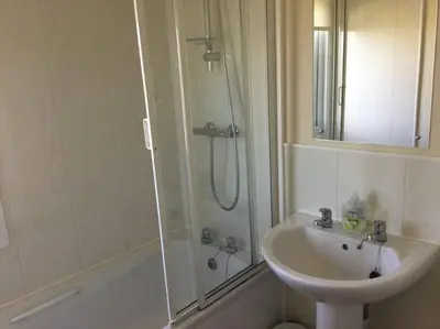 a bathroom with a sink and a shower next to a toilet at Marios Lodge in Padstow