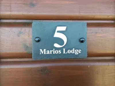 a sign that says maronis lodge on a wooden wall at Marios Lodge in Padstow