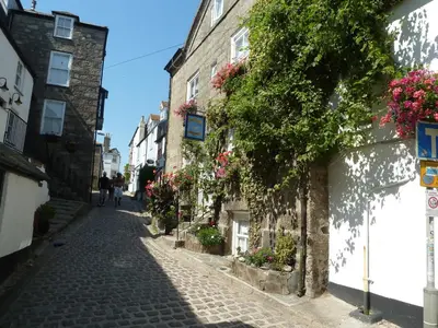 a cobblestone street in an old town with flowers at Grey Mullet Guesthouse in St Ives