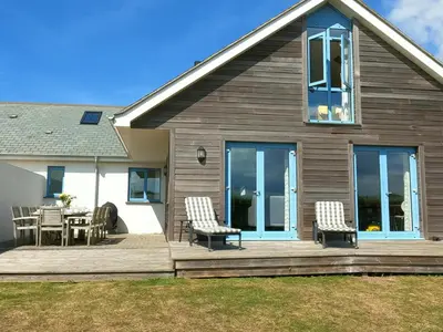 a house with a deck with chairs and a table at Bay Retreat - Widemouth Bay Bude Cornwall in Bude