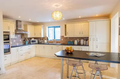a kitchen with white cabinets and a black counter top at Bay Retreat - Widemouth Bay Bude Cornwall in Bude
