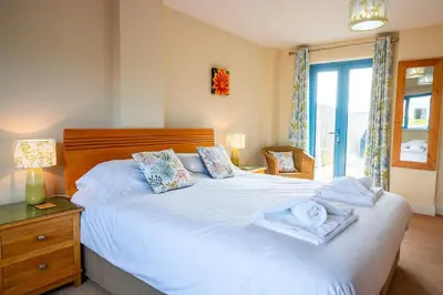 a bedroom with a large white bed and a window at Bay Retreat - Widemouth Bay Bude Cornwall in Bude
