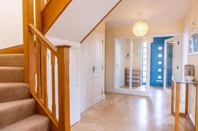 a hallway of a home with stairs and a chandelier at Bay Retreat - Widemouth Bay Bude Cornwall in Bude
