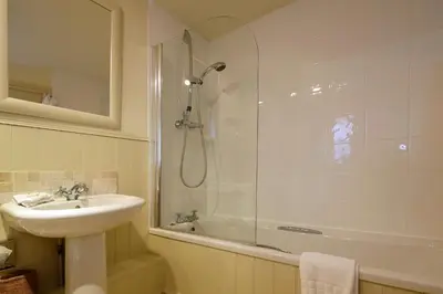 a bathroom with a shower and a sink and a tub at Driftwood B&B in Porthscatho