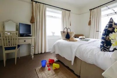 a bedroom with a bed with a television and a crib at Driftwood B&B in Porthscatho