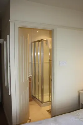 a bedroom with a glass door leading to a bathroom at Driftwood B&B in Porthscatho