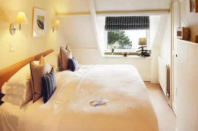a bedroom with a large white bed with a window at Driftwood B&B in Porthscatho