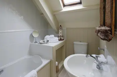 a bathroom with a sink and a toilet and a mirror at Driftwood B&B in Porthscatho
