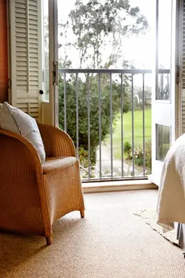a wicker chair sitting in front of a sliding glass door at Driftwood B&B in Porthscatho