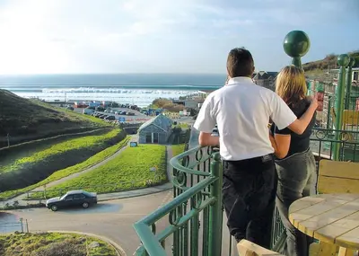 two people standing on a balcony looking at the ocean at Beachcombers in Porth