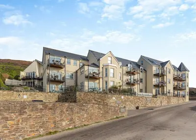 an apartment building on the side of a stone wall at Beachcombers in Porth