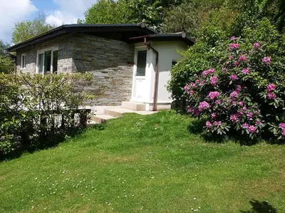 a stone house with a white door and some flowers at Kiberick Cottage at Crackington Haven, near Bude and Boscastle, Cornwall in Bude