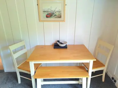 a wooden table with two chairs and a bowl on it at Kiberick Cottage at Crackington Haven, near Bude and Boscastle, Cornwall in Bude