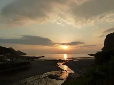 a sunset on a beach with the sun setting at Kiberick Cottage at Crackington Haven, near Bude and Boscastle, Cornwall in Bude