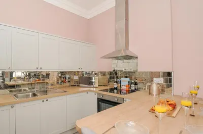 a kitchen with white cabinets and a wooden counter top at The Stannary in Helston