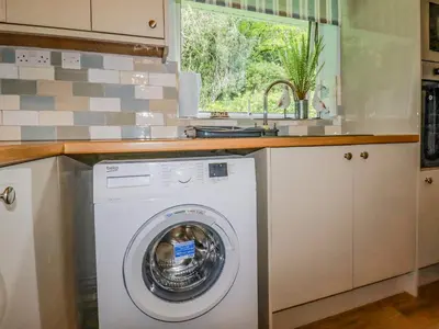 a kitchen with a washing machine under a counter at Woodside in Liskeard