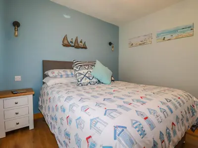a bedroom with a bed with a white bedspread and a night stand at Woodside in Liskeard
