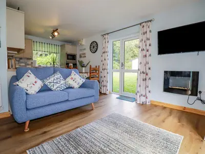 a living room with a blue couch and a fireplace at Woodside in Liskeard