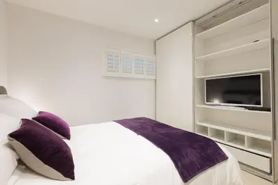 a bedroom with a bed with purple pillows and a tv at The Breakers in Carbis Bay