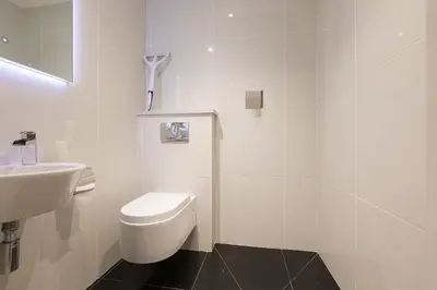 a white bathroom with a toilet and a sink at The Breakers in Carbis Bay