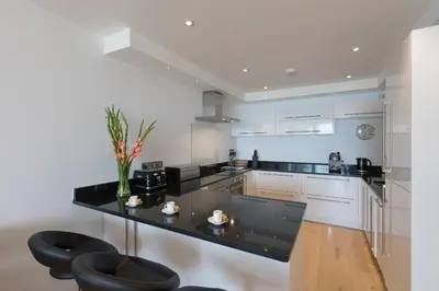 a kitchen with a black counter and some chairs at The Breakers in Carbis Bay