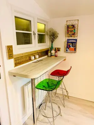 a kitchen with two stools and a counter and two windows at SHINE CHALET - UNIQUE & COMFORTABLE ACCOMMODATION in Redruth