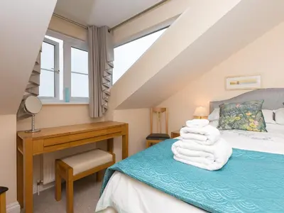 a bedroom with a bed with a desk and towels at Laurellie in Carbis Bay