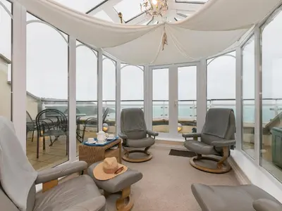 a room with chairs and a table and windows at Laurellie in Carbis Bay
