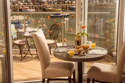 a table with a plate of food and two chairs at The Old Bridge House in Looe