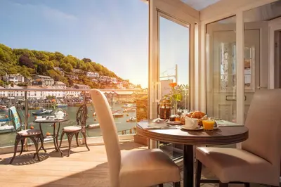 a balcony with a table and chairs and a view of a harbor at The Old Bridge House in Looe
