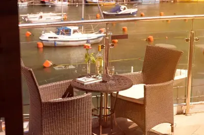 a table and chairs with a view of a marina at The Old Bridge House in Looe