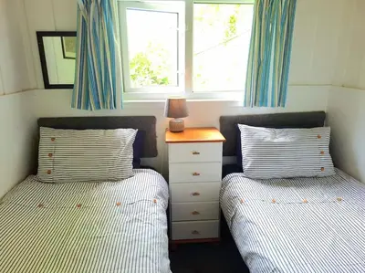a bedroom with two beds and a dresser and a window at Gorgeous Cottage at Crackington Haven, near Bude and Boscastle, Cornwall in Bude