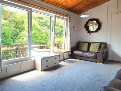 a living room with a couch and a large window at Parada Cottage at Crackington Haven, near Bude and Boscastle, Cornwall in Bude