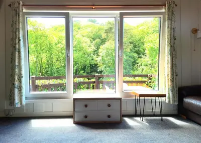 a living room with a large window and a table at Parada Cottage at Crackington Haven, near Bude and Boscastle, Cornwall in Bude