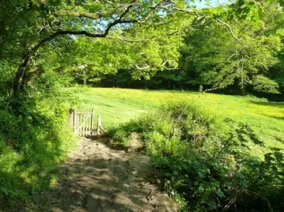 a path in a field with a fence and trees at Parada Cottage at Crackington Haven, near Bude and Boscastle, Cornwall in Bude