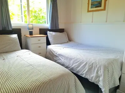 a bedroom with two beds and a dresser and a window at Parada Cottage at Crackington Haven, near Bude and Boscastle, Cornwall in Bude