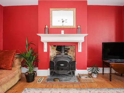 a living room with a fireplace with red walls at Sunset House in Newquay
