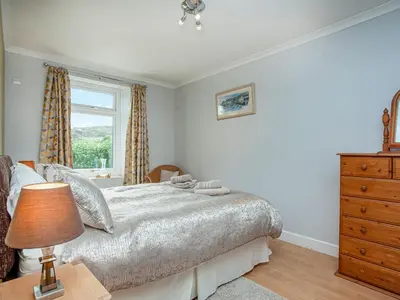 a bedroom with a bed with a dresser and a window at Tanglewood in Bugle
