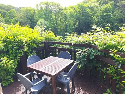 a wooden table and chairs on a wooden deck at Bantry Cottage at Crackington Haven, near Bude and Boscastle, Cornwall in Bude