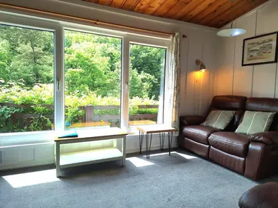 a living room with a couch and a large window at Bantry Cottage at Crackington Haven, near Bude and Boscastle, Cornwall in Bude