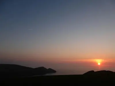 a sunset with the sun setting over the ocean at Bantry Cottage at Crackington Haven, near Bude and Boscastle, Cornwall in Bude