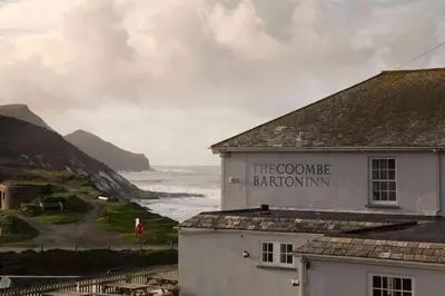 a white building with a sign that reads the come baton inn at Kallowen Cottage at Crackington Haven, near Bude and Boscastle, Cornwall in Bude