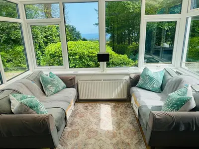 a living room with two couches and large windows at Bay View Cottage in St Austell