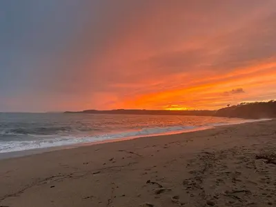 a sunset on a beach with the ocean at Bay View Cottage in St Austell