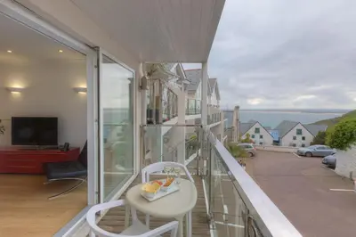 a balcony with a white chair and a view of the ocean at Indigo in St Ives