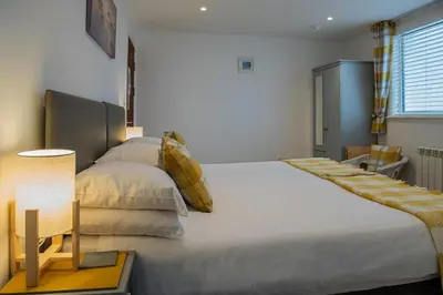 a bedroom with two beds and a table with a lamp at Trevarrian Lodge in Newquay