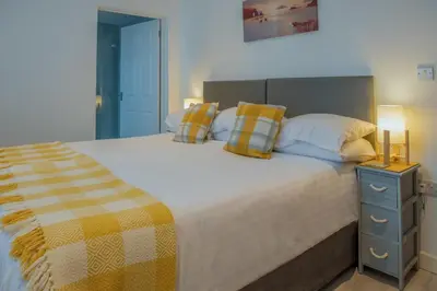 a bedroom with a large bed with yellow and white pillows at Trevarrian Lodge in Newquay